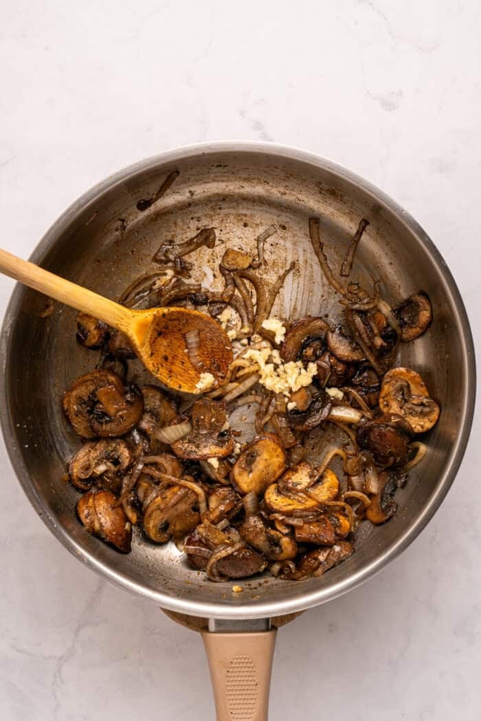 Juicy beef burgers are topped with slices of melty Swiss cheese and savory sauteed mushrooms in this Mushroom Swiss Burger recipe. Sauteed mushrooms in a pan