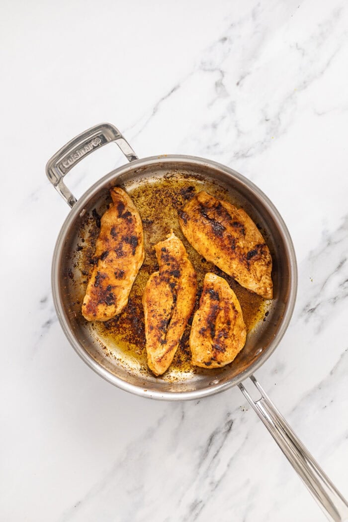 Juicy chicken breasts are cooked in a creamy pesto sauce with roasted tomatoes in this Pesto Chicken recipe. Cooked chicken breasts in a pan