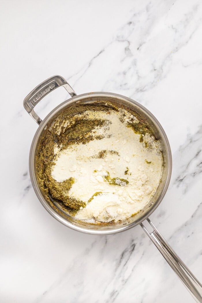 Juicy chicken breasts are cooked in a creamy pesto sauce with roasted tomatoes in this Pesto Chicken recipe. Heavy cream added to pesto in a pan