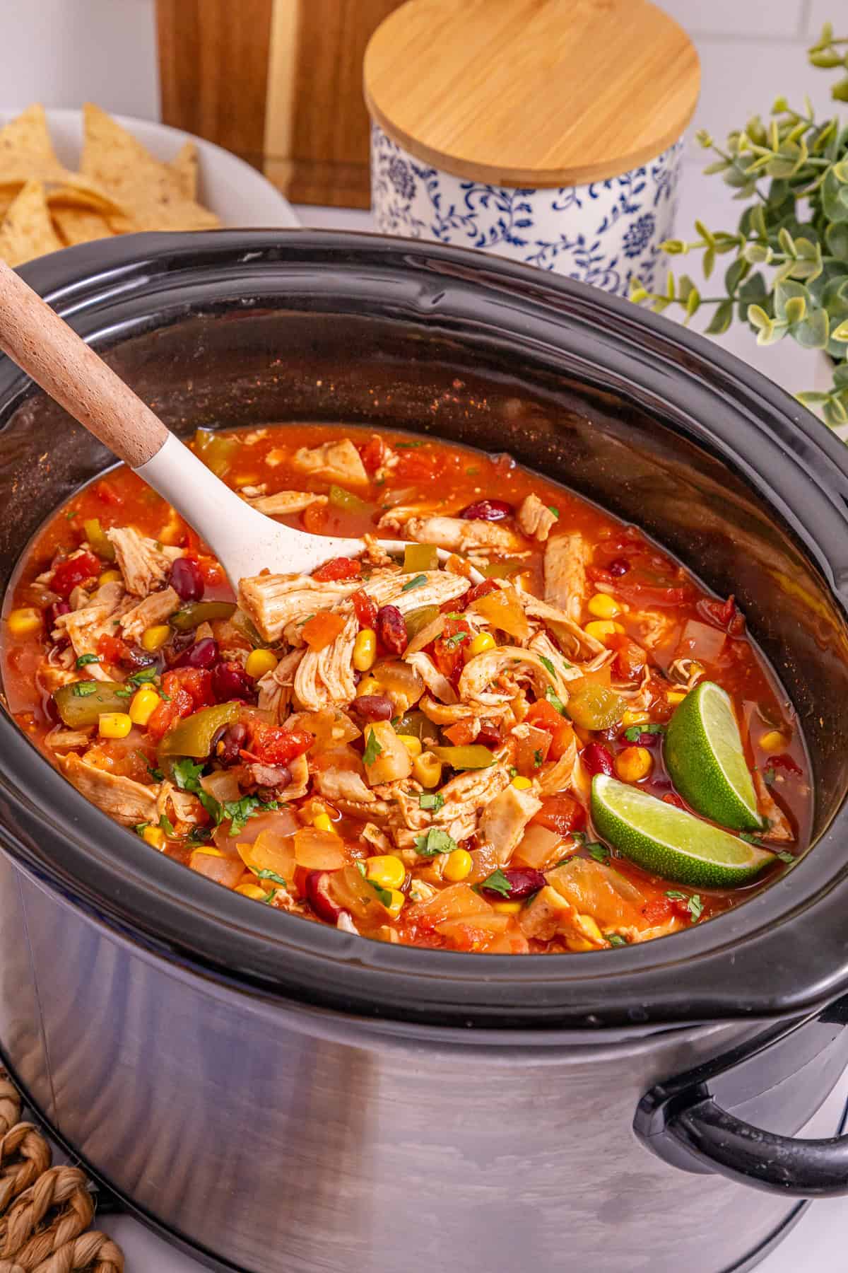 This Slow Cooker Chicken Chili is a “set it and forget it” recipe that’s perfect for busy weeknights. Hearty, filling, and super easy to make! A spoon stirring slow cooker chicken chili