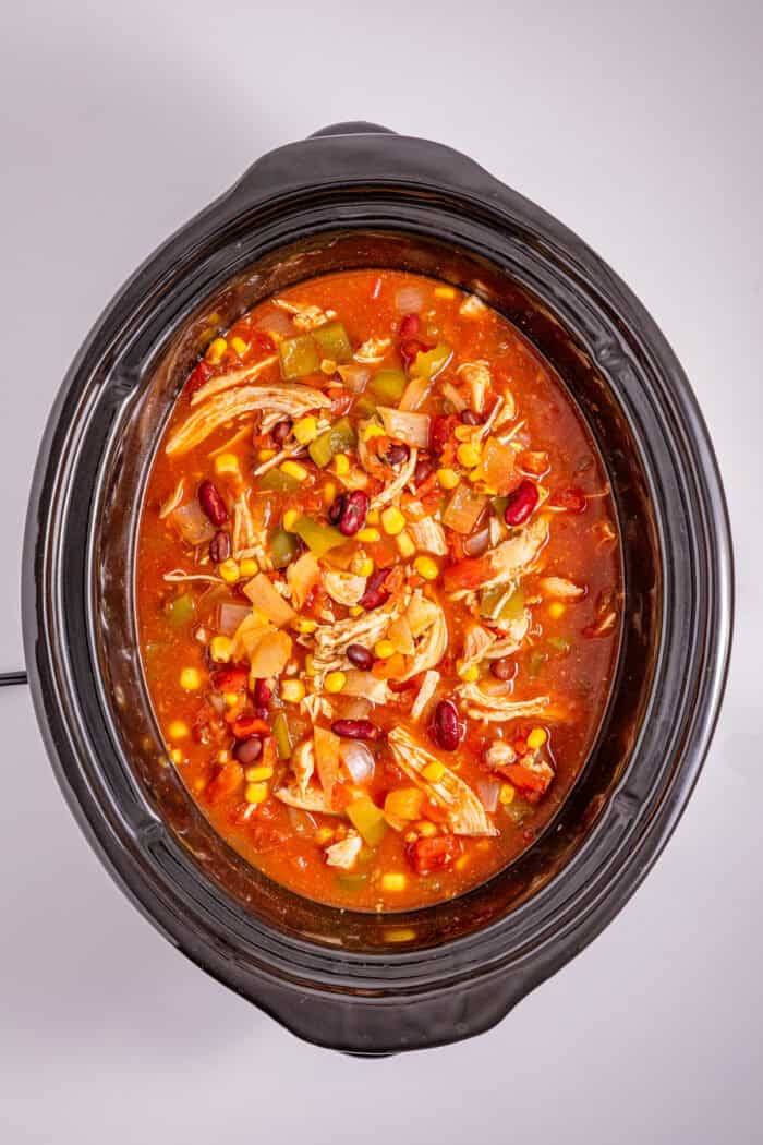 This Slow Cooker Chicken Chili is a “set it and forget it” recipe that’s perfect for busy weeknights. Hearty, filling, and super easy to make! Overhead view of chicken chili in the slow cooker