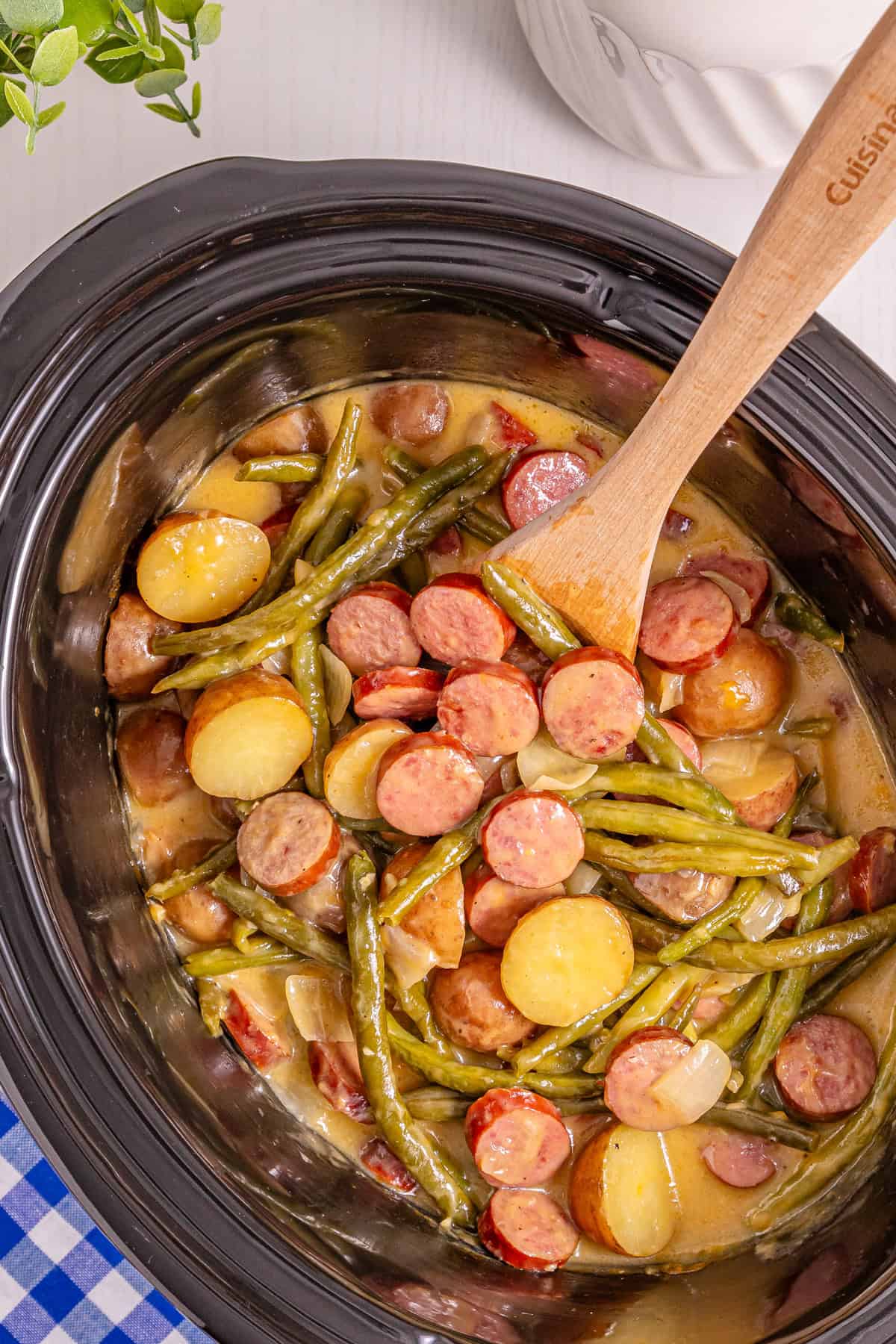 A wooden spoon stirring swamp potatoes in the slow cooker