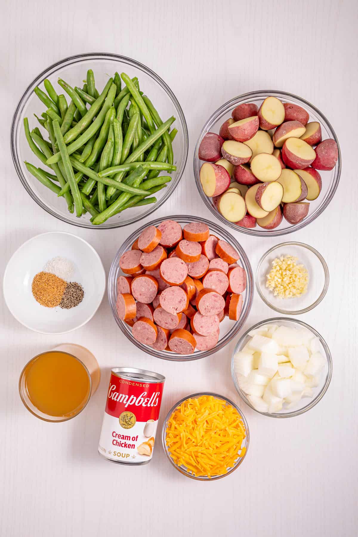 Baby potatoes, smoked sausage, and green beans are slow-cooked in Cajun seasoning and cream of chicken soup in this Crockpot Swamp Potatoes recipe. It’s an easy, flavorful dump-and-go recipe that’s perfect for busy weekends. Overhead view of ingredients needed to make crockpot swamp potatoes