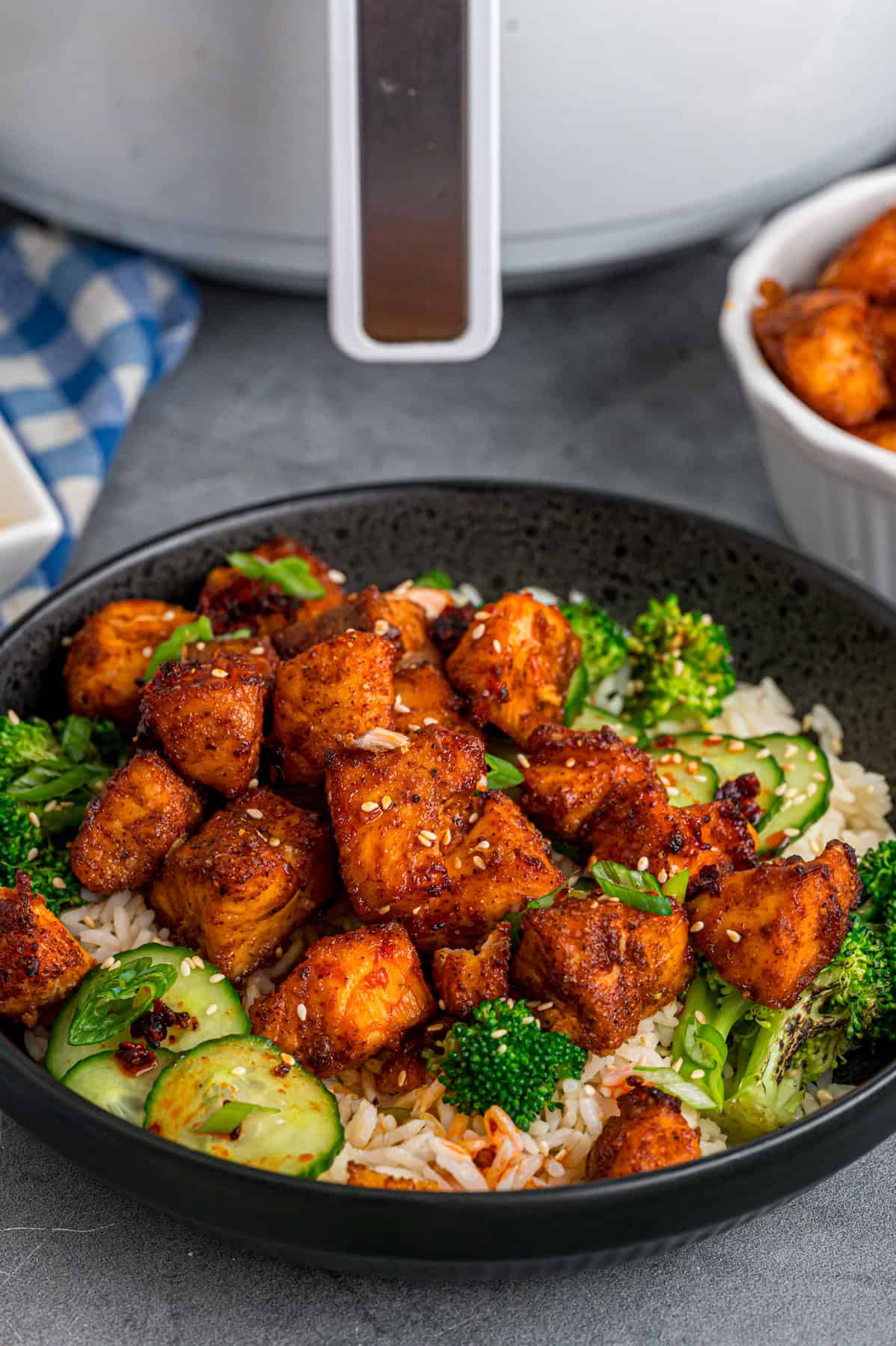 A bowl of air fryer salmon bites in front of the air fryer