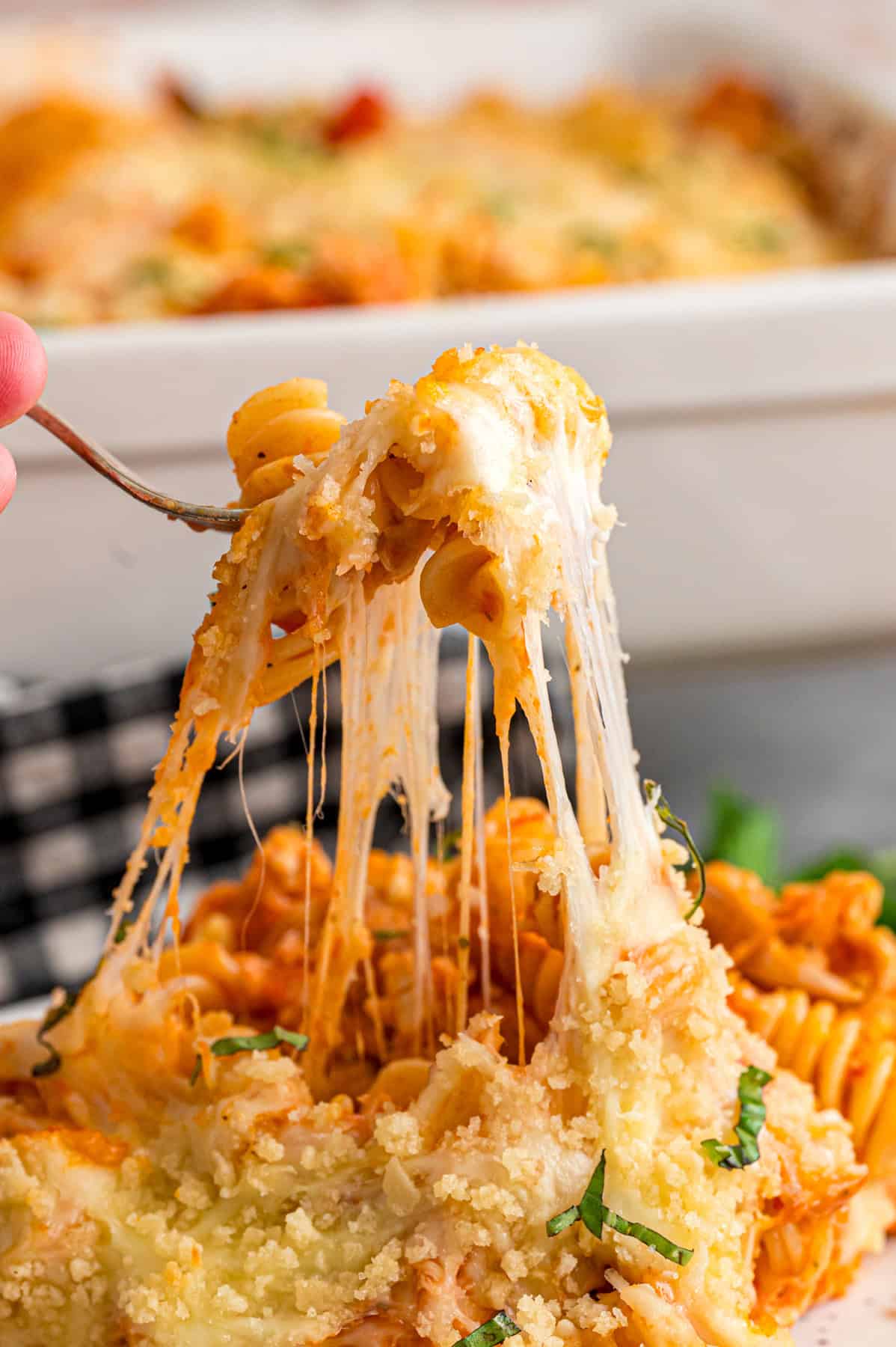 A bite of chicken parmesan casserole on a fork showing the cheesiness