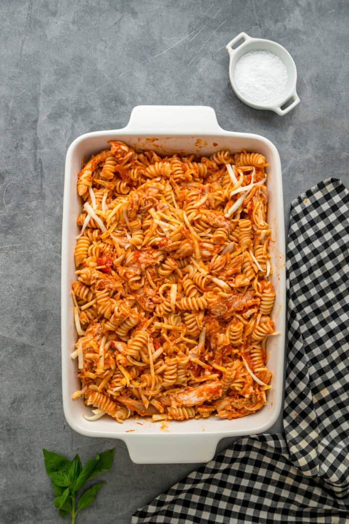 Pasta and chicken coated in marinara sauce in a baking dish