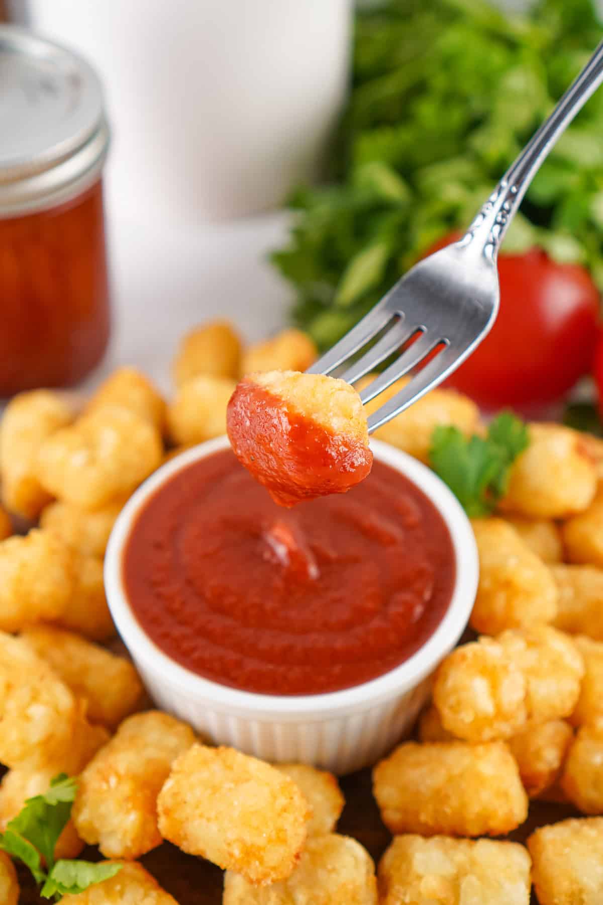 A tater tot on a fork dipped in homemade ketchup