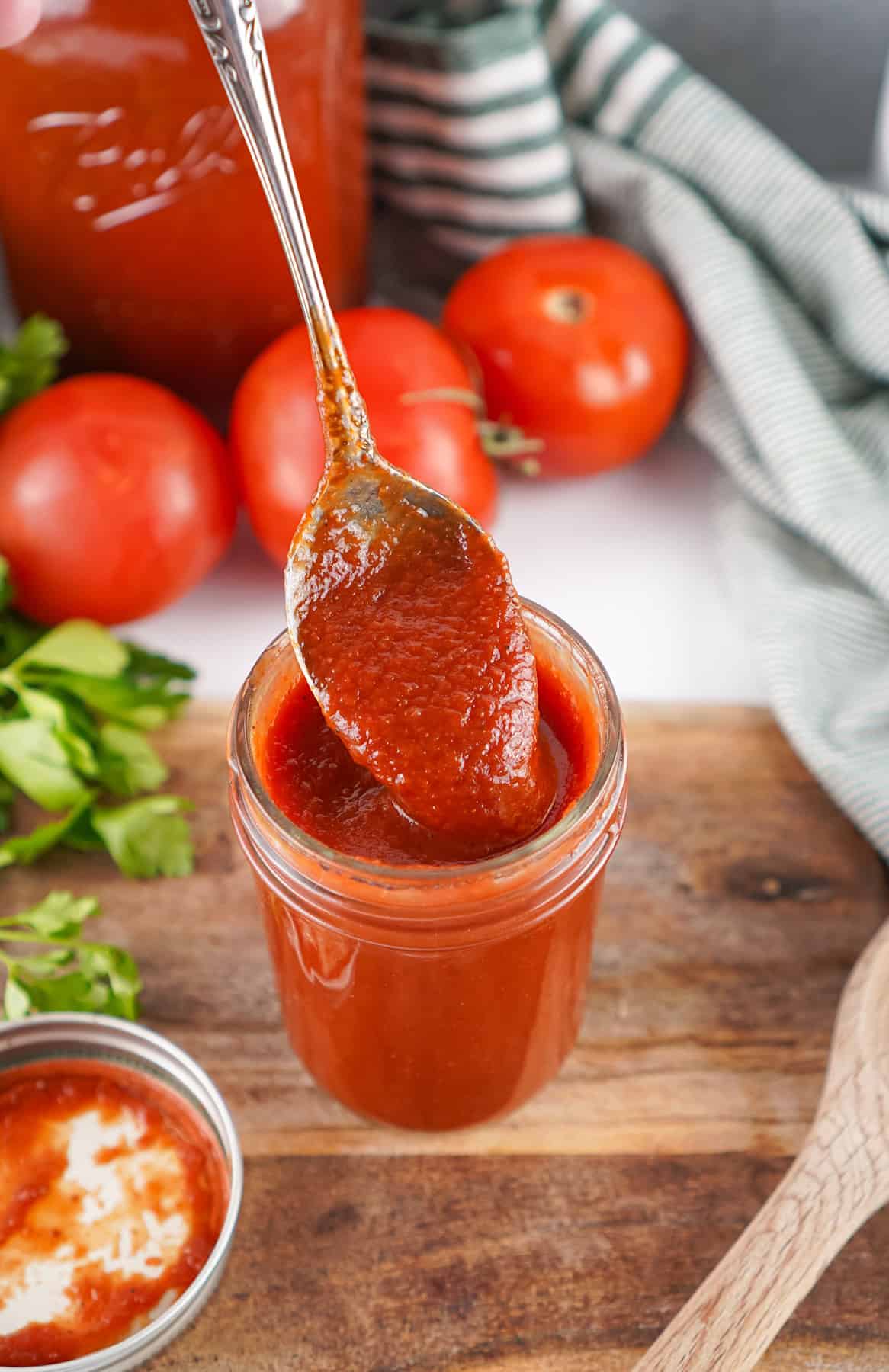 It only takes a handful of ingredients and a bit of simmering to make Homemade Ketchup that's far better than store-bought. A spoon pulling out of a jar of homemade ketchup