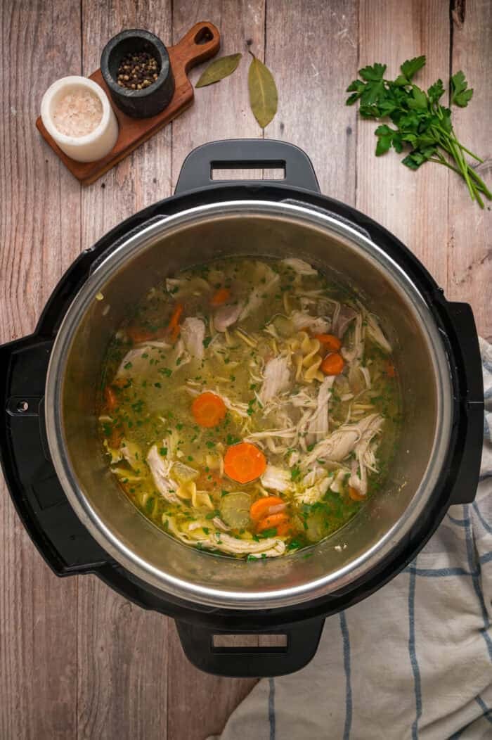 With egg noodles, shredded chicken, carrots, and celery, this Instant Pot Chicken Noodle Soup is classic comfort food made quick and easy. Overhead view of chicken noodle soup in the Instant Pot