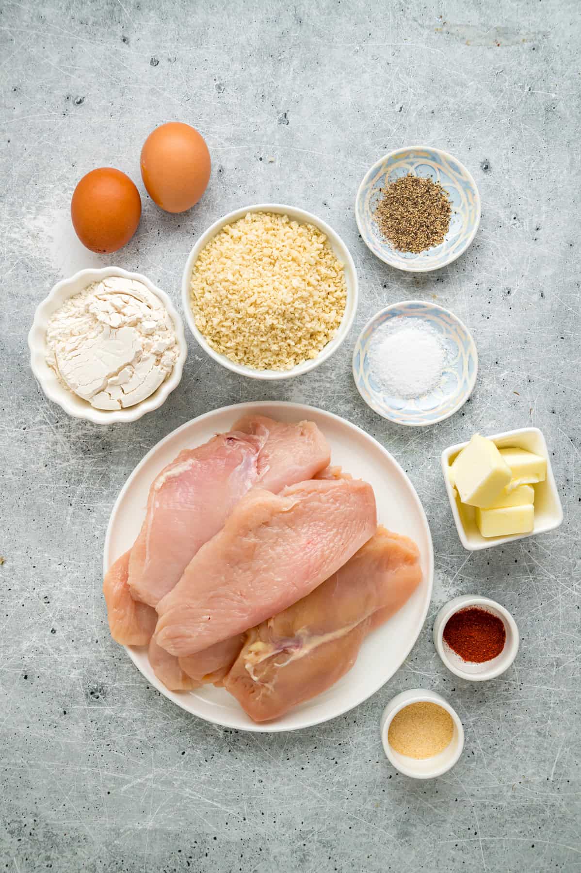 Coated in seasoned panko breadcrumbs, this oven fried chicken is crispy on the outside and juicy on the inside. Quick & easy! Overhead view of ingredients needed to make oven fried chicken