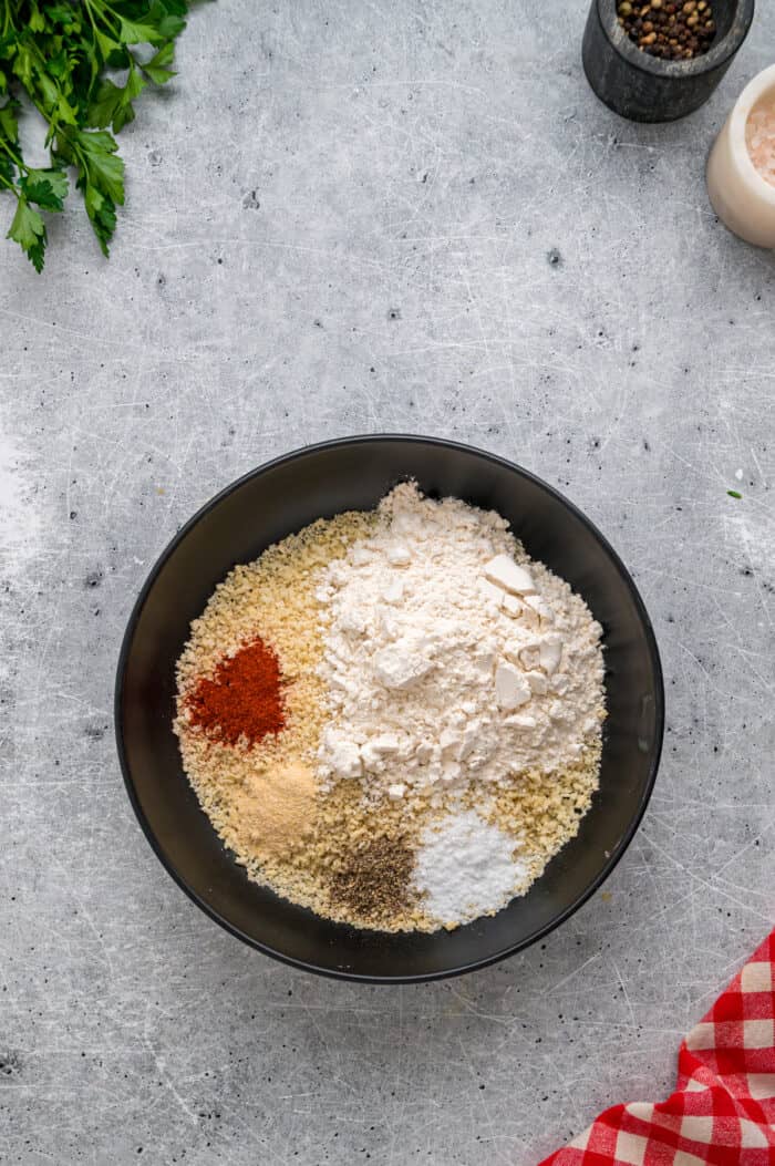 Coated in seasoned panko breadcrumbs, this oven fried chicken is crispy on the outside and juicy on the inside. Quick & easy! Breadcrumbs, flour, and seasonings in a bowl