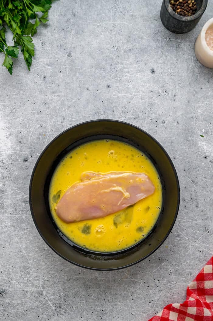 Coated in seasoned panko breadcrumbs, this oven fried chicken is crispy on the outside and juicy on the inside. Quick & easy! A chicken strip in a bowl of egg