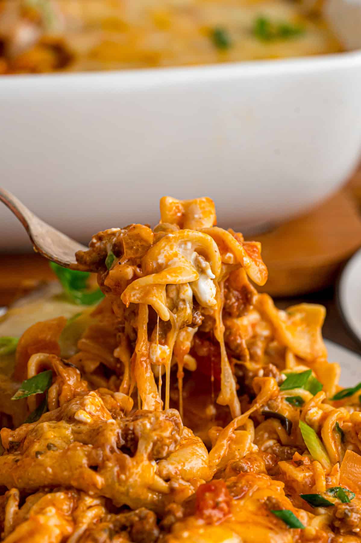 With noodles coated in sour cream, meat sauce, and lots of cheese, this sour cream noodle bake is quick, easy & comforting. A bite of sour cream noodle bake on a fork
