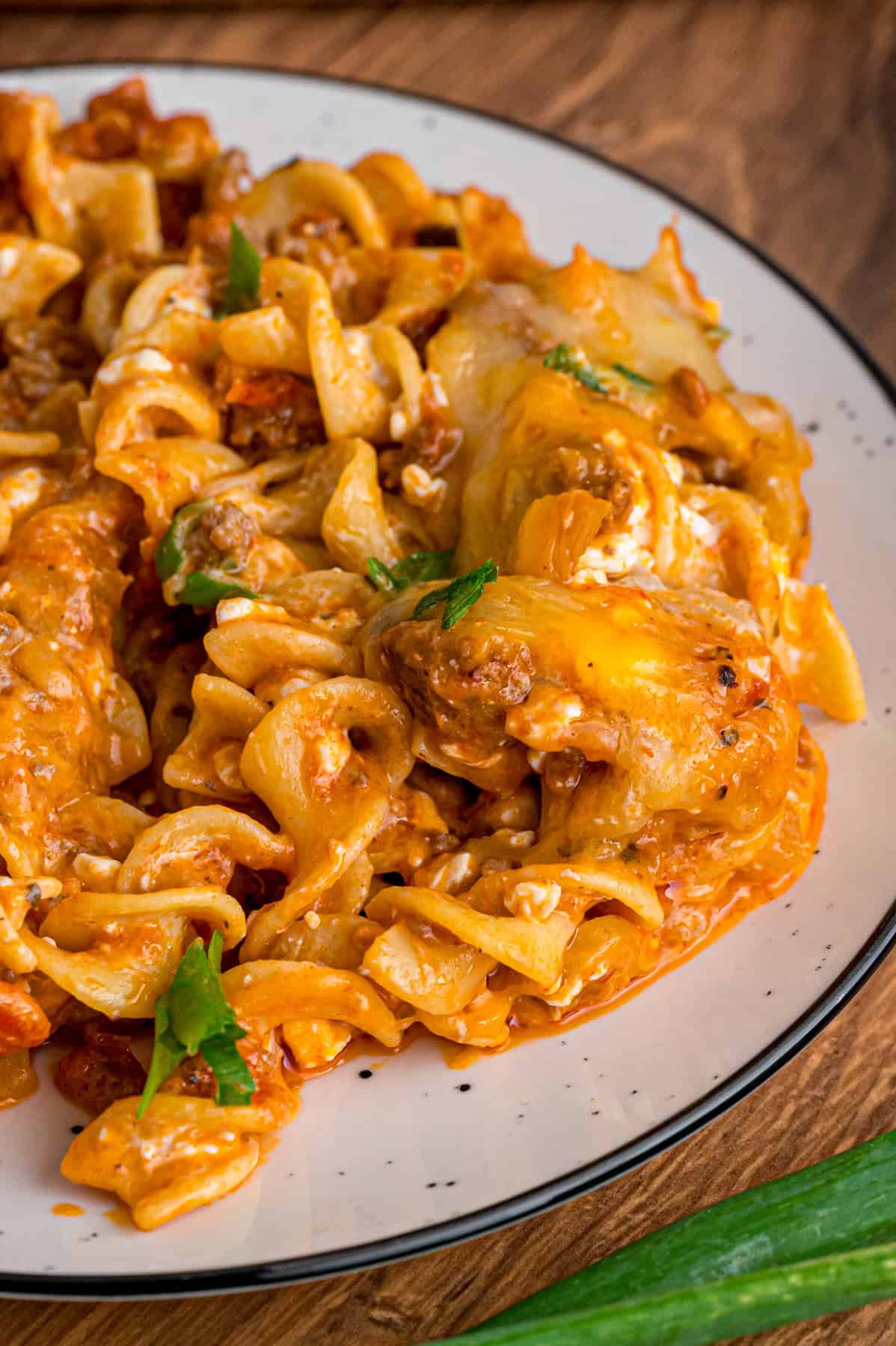 With noodles coated in sour cream, meat sauce, and lots of cheese, this sour cream noodle bake is quick, easy & comforting. A white plate of sour cream noodle bake