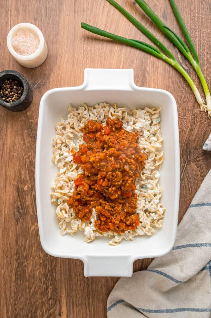 With noodles coated in sour cream, meat sauce, and lots of cheese, this sour cream noodle bake is quick, easy & comforting. Meat sauce spooned on top of the noodles