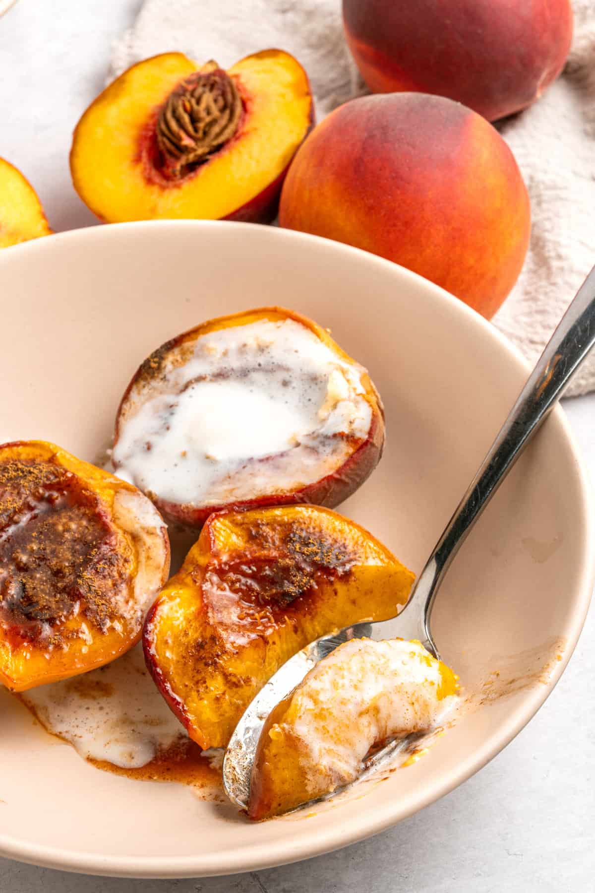 A spoon in a bowl of baked peaches