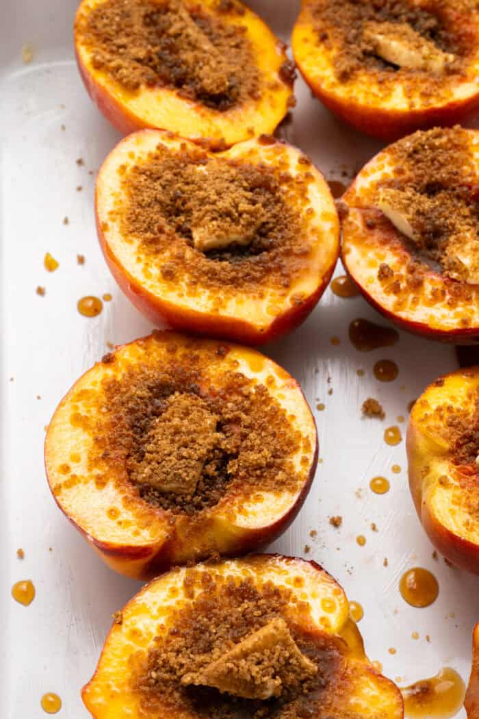 Peach halves topped with cubes of butter and sprinkled with cinnamon sugar