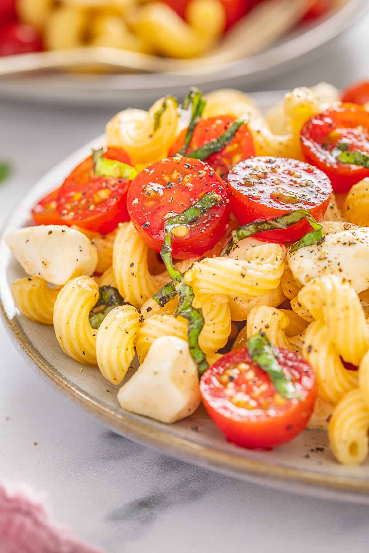 Fresh mozzarella, tomatoes, basil, and pasta are tossed with a lemony vinaigrette in this Caprese Pasta Salad. A plate of caprese pasta salad
