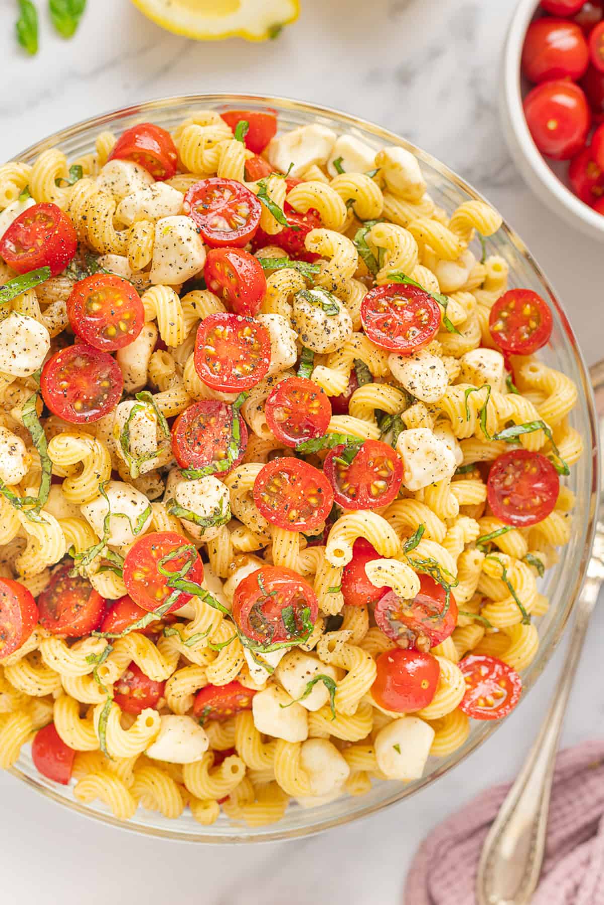 Fresh mozzarella, tomatoes, basil, and pasta are tossed with a lemony vinaigrette in this Caprese Pasta Salad. Overhead view of a big bowl of caprese pasta salad