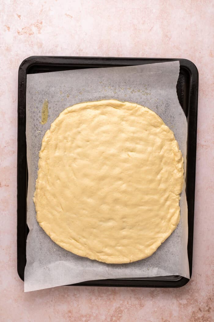 Unbaked cottage cheese pizza crust on a baking sheet
