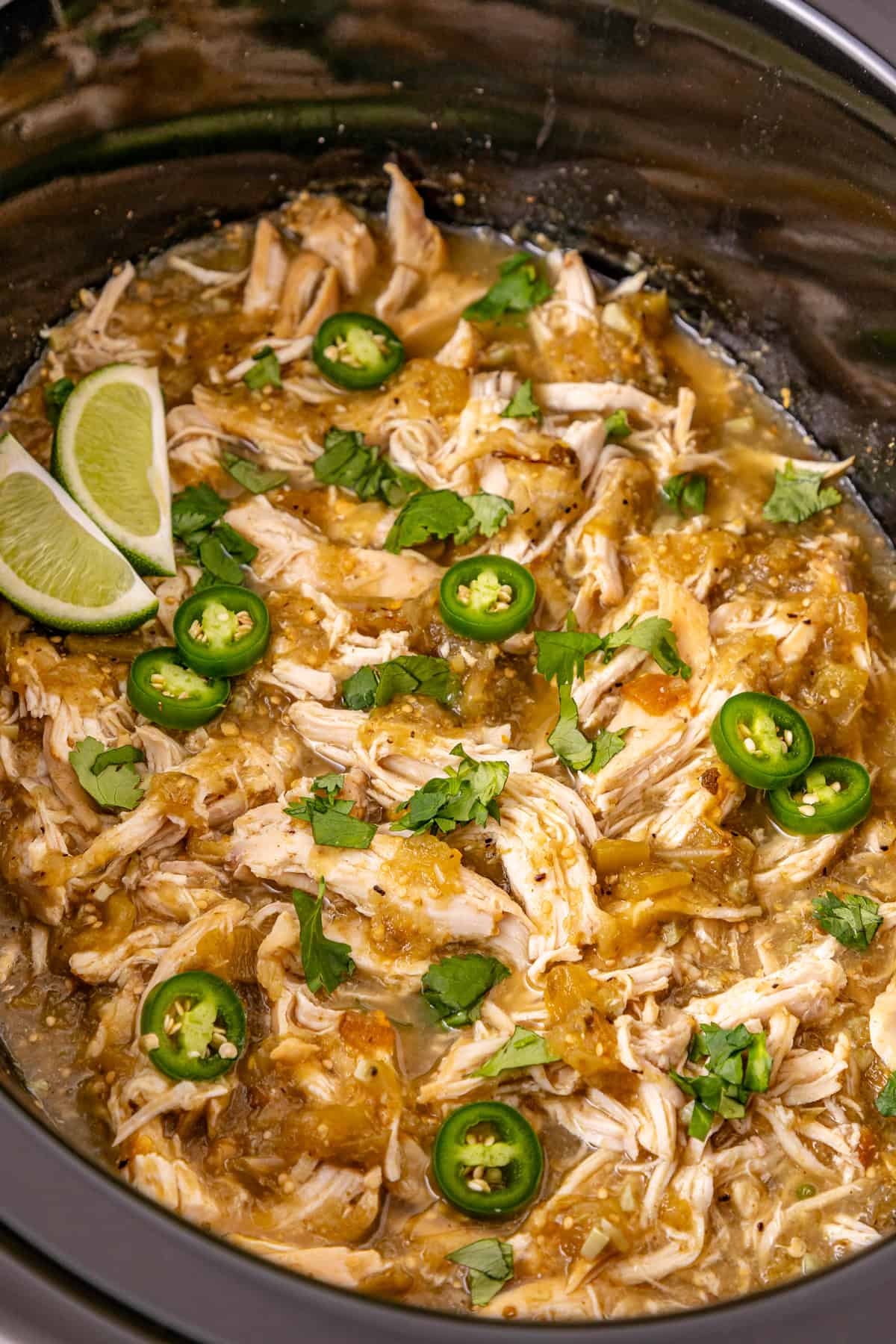 Chicken breast is slow cooked in salsa verde then shredded to make this Crockpot Salsa Verde Chicken. Easy dinner idea! Overhead view of crockpot salsa verde chicken in a black crockpot