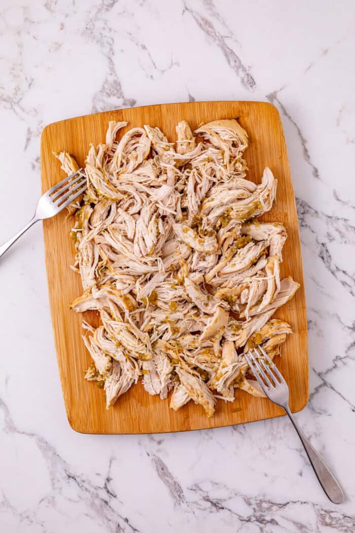 Chicken breast is slow cooked in salsa verde then shredded to make this Crockpot Salsa Verde Chicken. Easy dinner idea! Shredded chicken on a cutting board