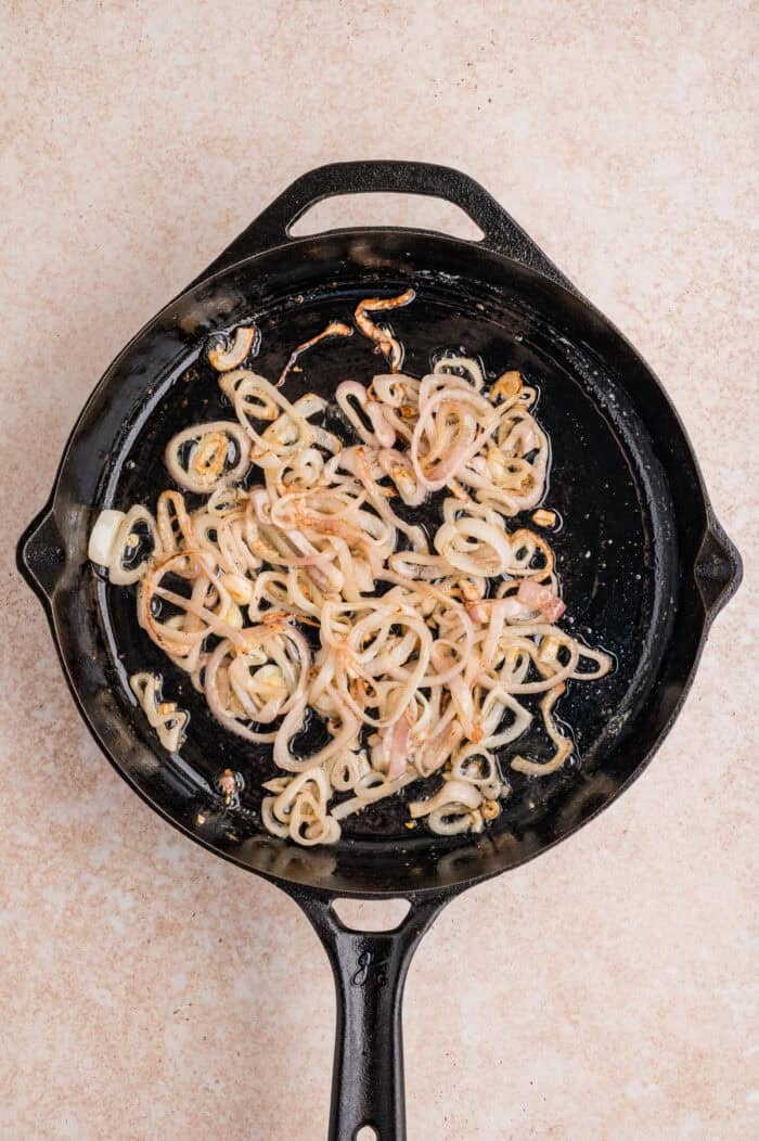 These Green Beans Almondine are a quick and easy side dish made with tender crisp green beans, buttery shallots, and toasted almonds. Sliced shallots in a skillet