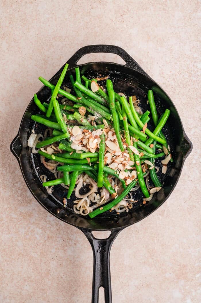 These Green Beans Almondine are a quick and easy side dish made with tender crisp green beans, buttery shallots, and toasted almonds. Fresh green beans and shallots in a skillet