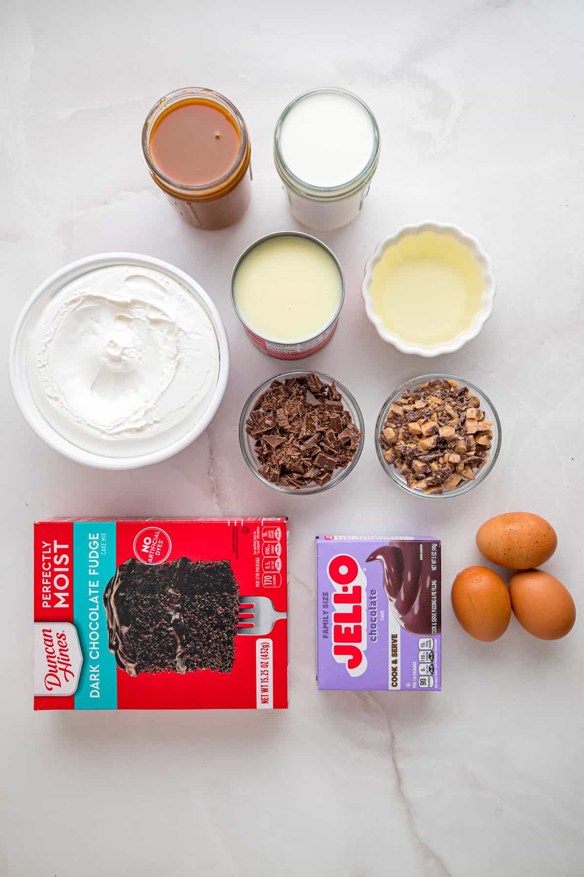 Chocolate cake is drizzled with sweetened condensed milk, caramel sauce, and whipped topping to make this decadent Better Than Sex Cake. Overhead view of ingredients needed to make better than sex cake