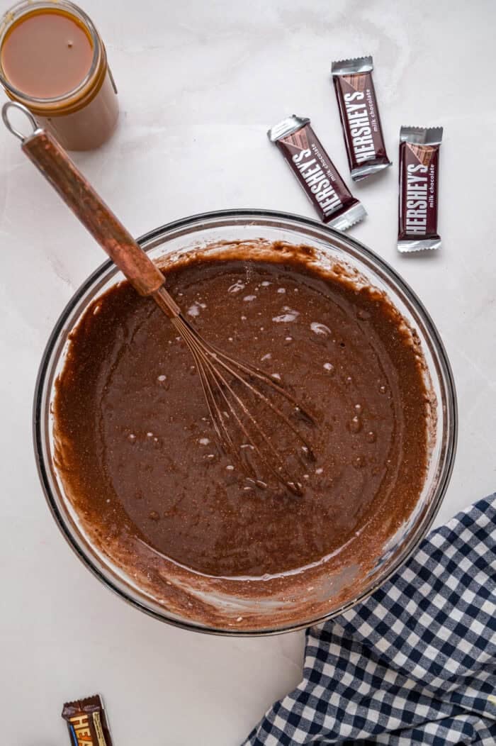 Chocolate cake is drizzled with sweetened condensed milk, caramel sauce, and whipped topping to make this decadent Better Than Sex Cake. Whisking chocolate cake batter in a bowl