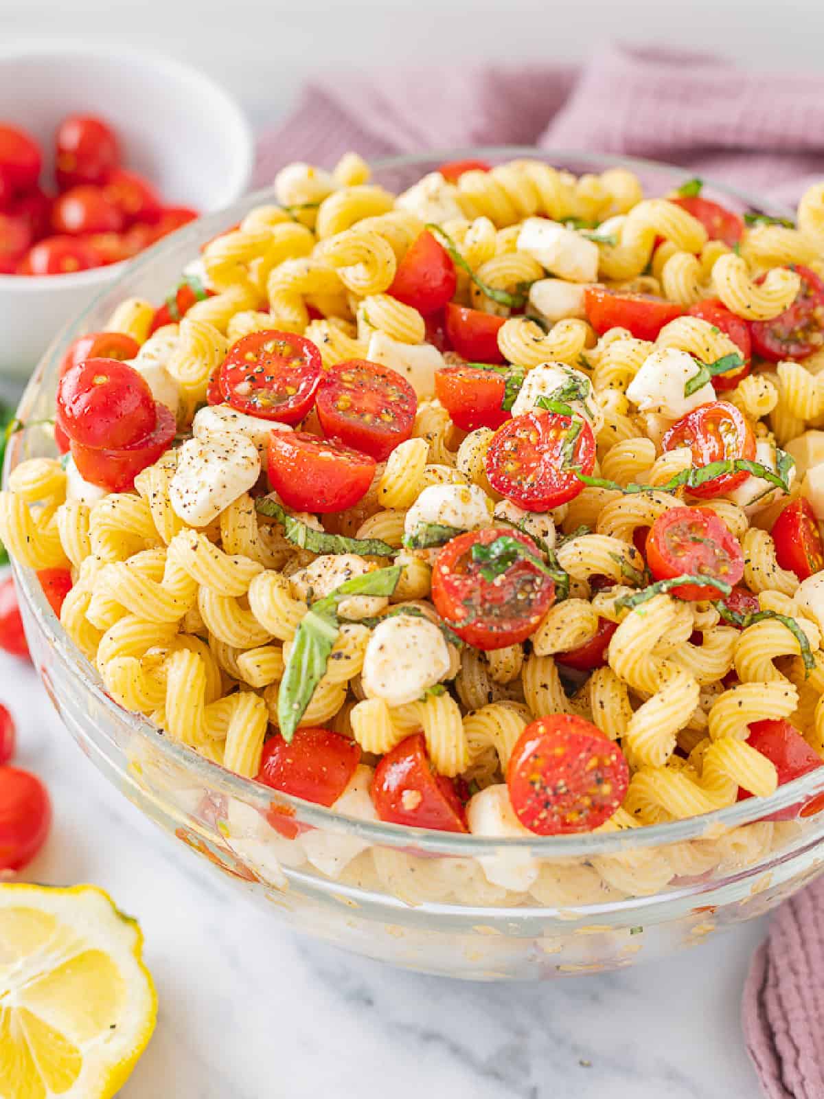 Fresh mozzarella, tomatoes, basil, and pasta are tossed with a lemony vinaigrette in this Caprese Pasta Salad. Caprese Pasta Salad in a bowl