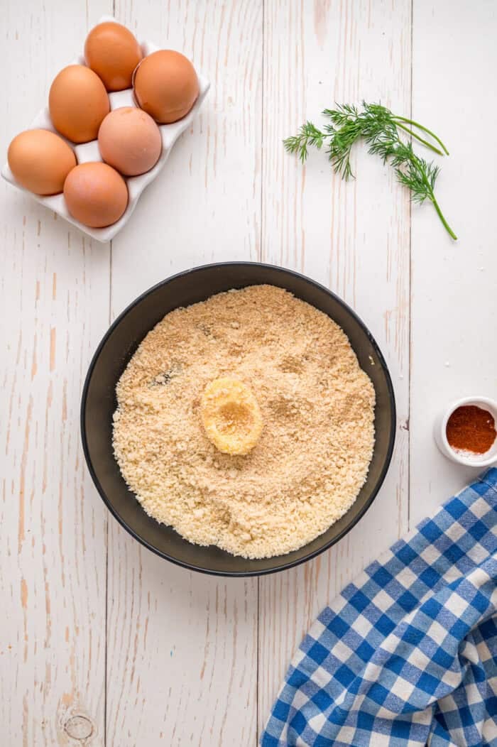 Fried Deviled Eggs are a fun twist on the classic, with hard-boiled egg whites coated in breadcrumbs and deep-fried. Half an egg white in a bowl of breadcrumbs