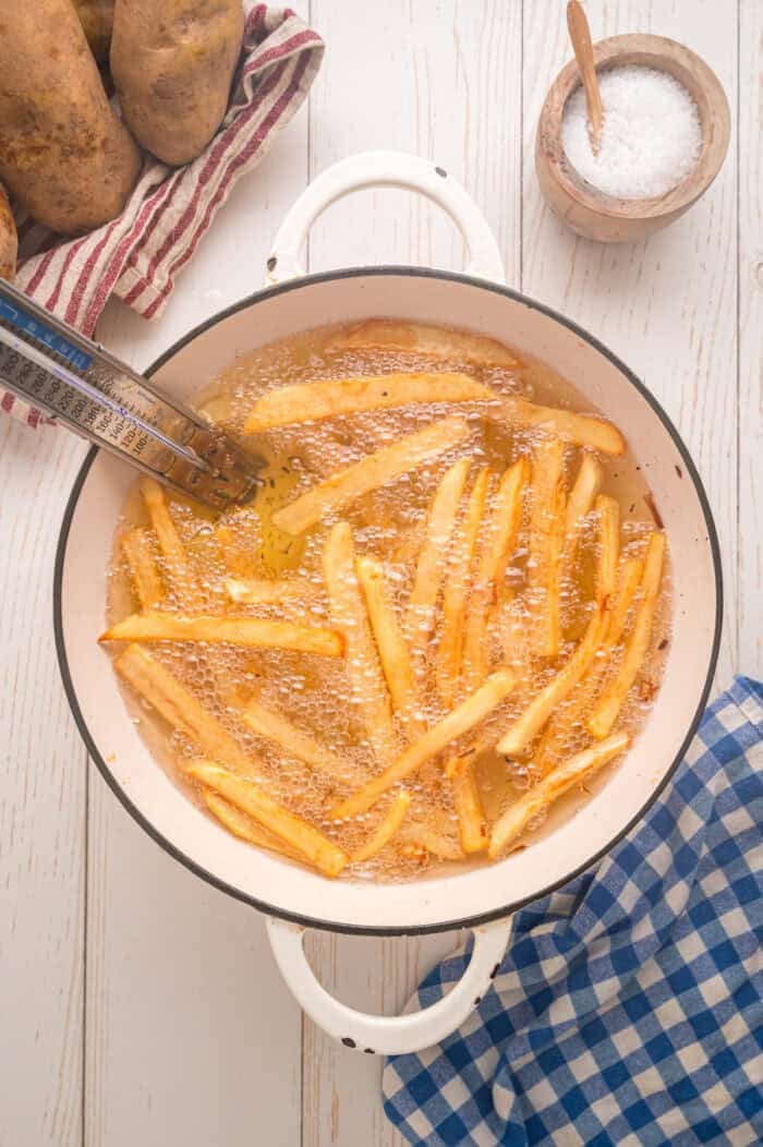 These easy homemade French Fries are made with just Russet potatoes, salt, and oil. Tender on the inside and crispy on the outside! Tongs pulled homemade fries from oil