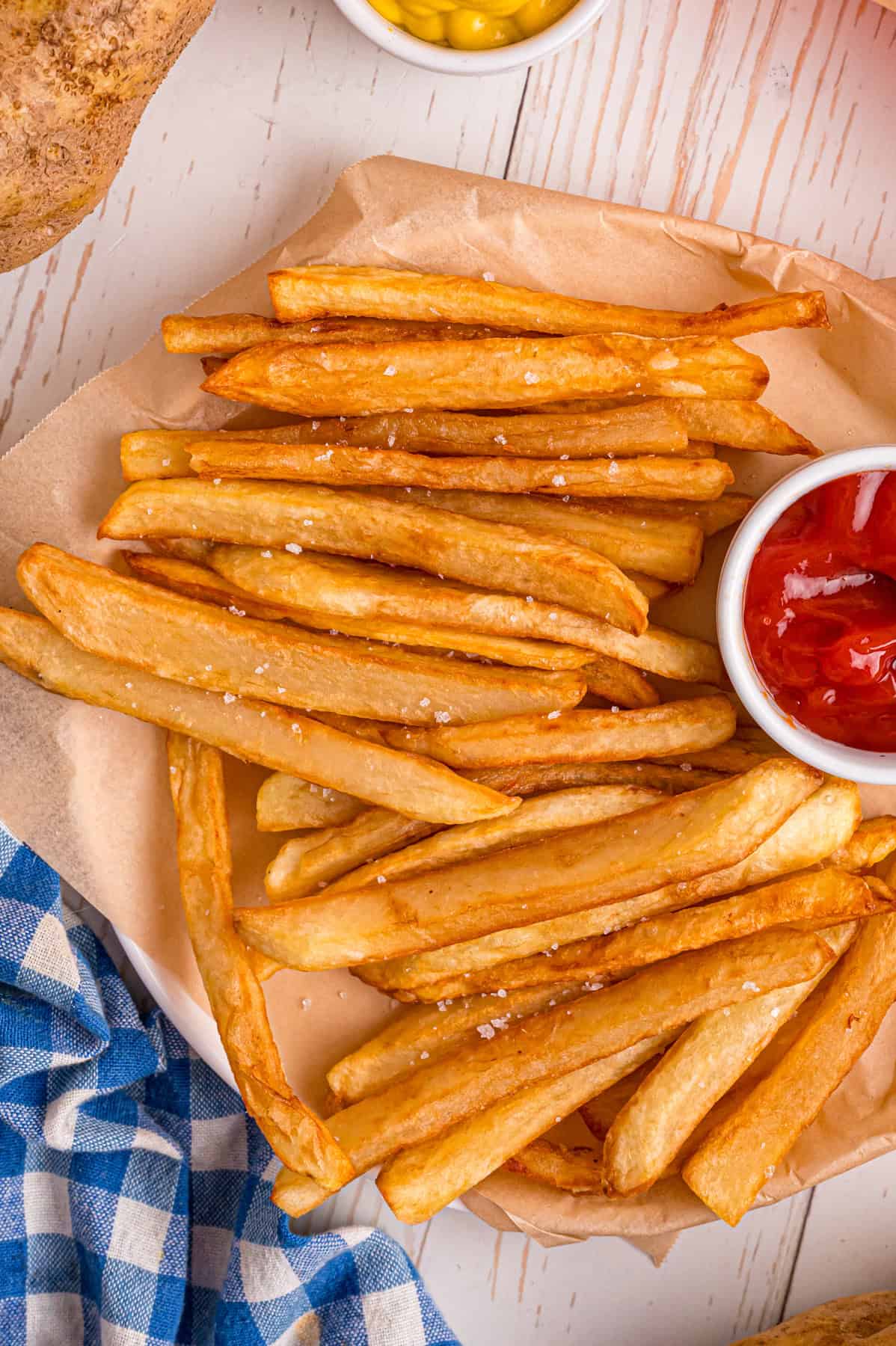 Overhead view of a plate of crispy homemade French fries with a dish of ketchup