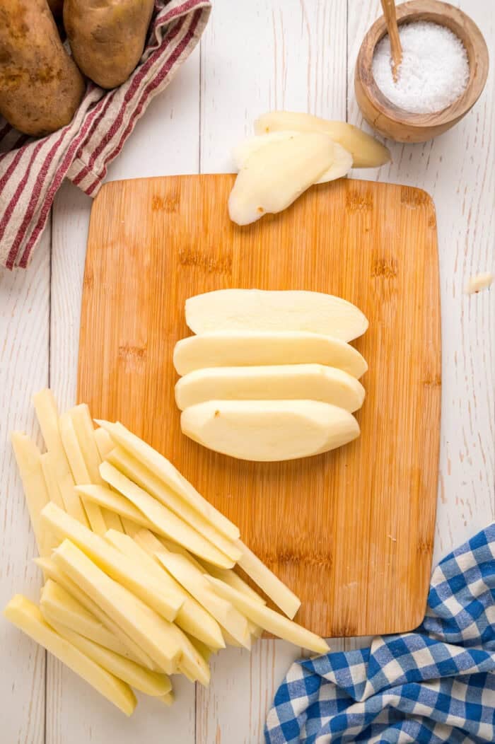 These easy homemade French Fries are made with just Russet potatoes, salt, and oil. Tender on the inside and crispy on the outside! Slicing a potato into homemade French fries