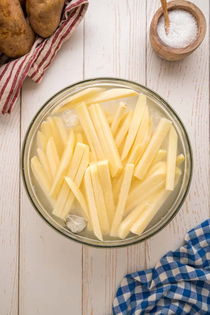 These easy homemade French Fries are made with just Russet potatoes, salt, and oil. Tender on the inside and crispy on the outside! Homemade fries soaking in water