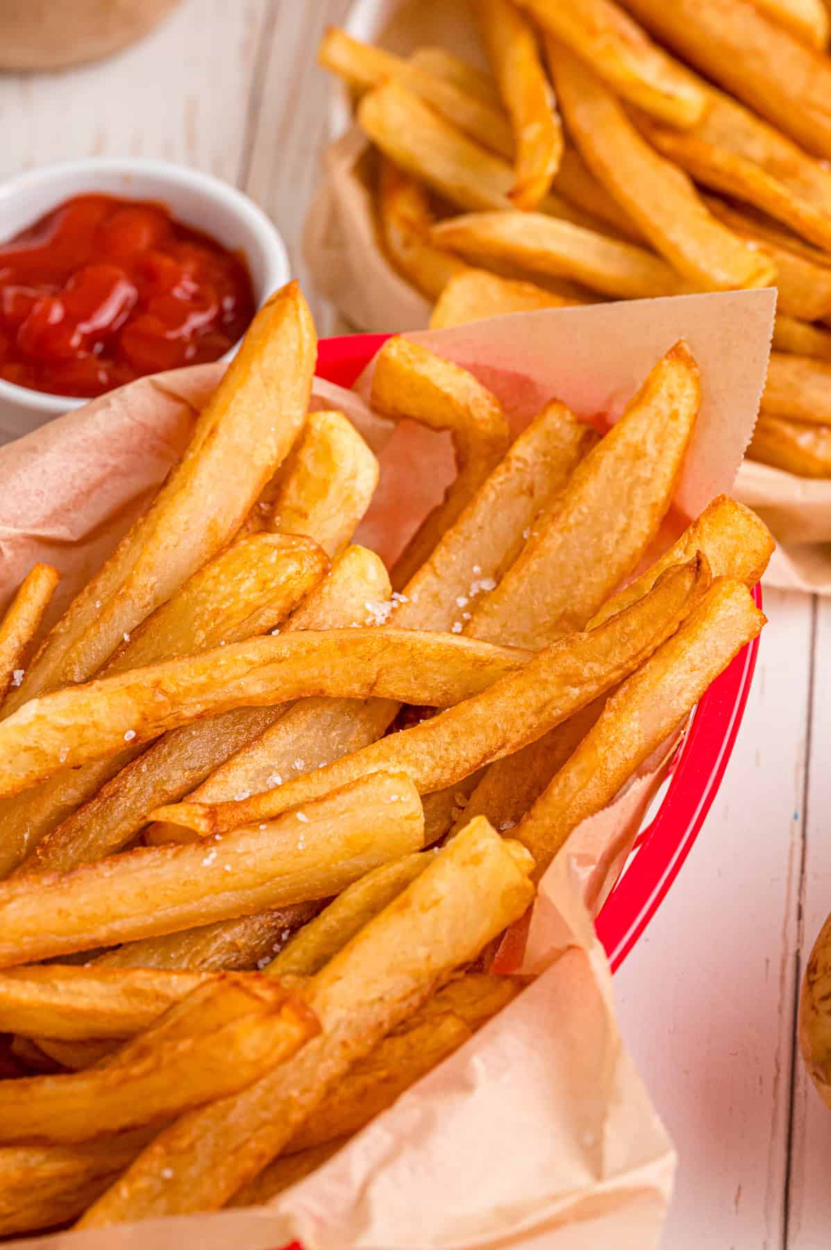 These easy homemade French Fries are made with just Russet potatoes, salt, and oil. Tender on the inside and crispy on the outside! A red basket of crispy homemade French fries