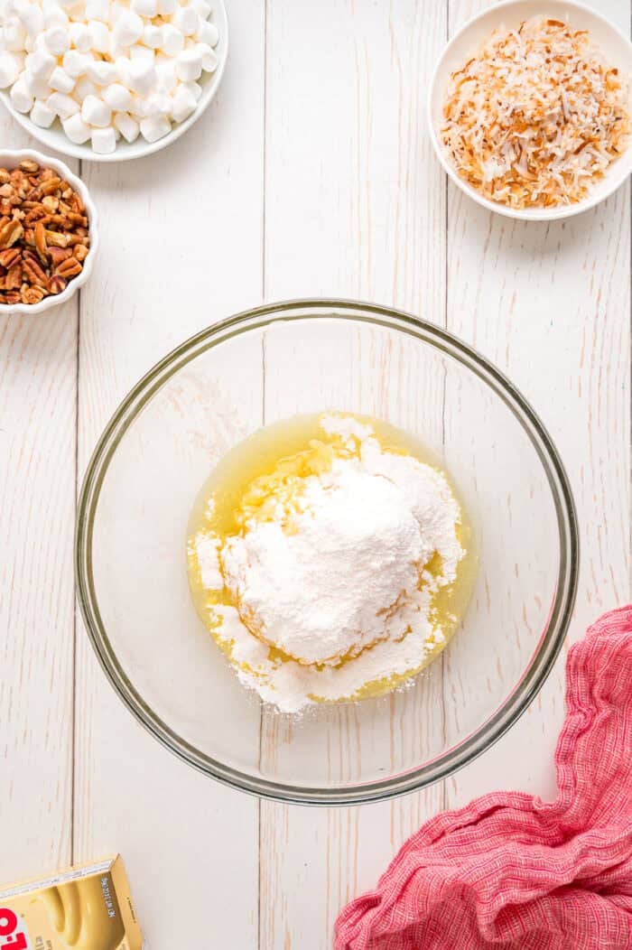 Pineapple Fluff is a quick and easy no-bake dessert that’s perfect for summer, with crushed pineapple, toasted coconut, and marshmallows. Crushed pineapple and instant pudding mix in a bowl