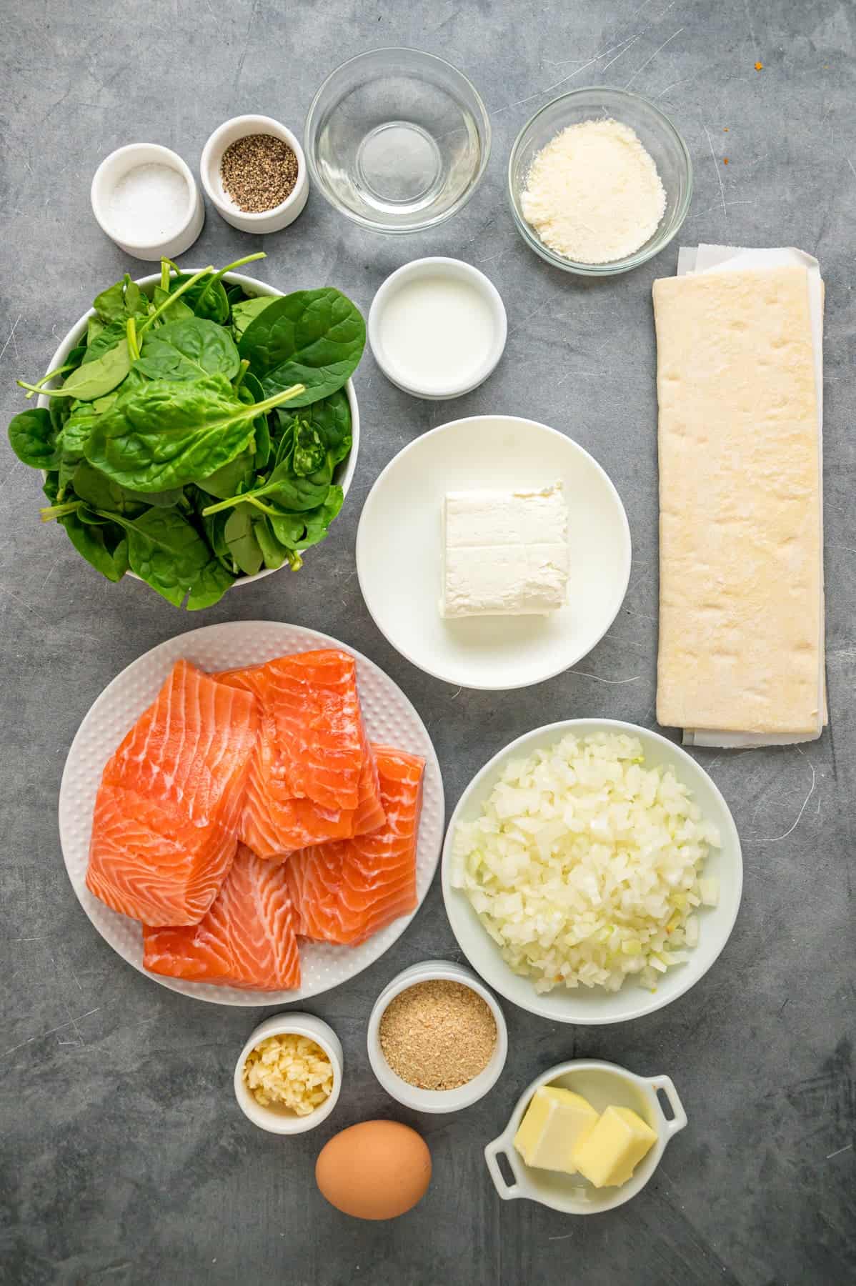 This Salmon Wellington recipe features tender salmon topped with a cream cheese spinach filling and wrapped in a flaky puff pastry. Overhead view of ingredients needed to make salmon wellington
