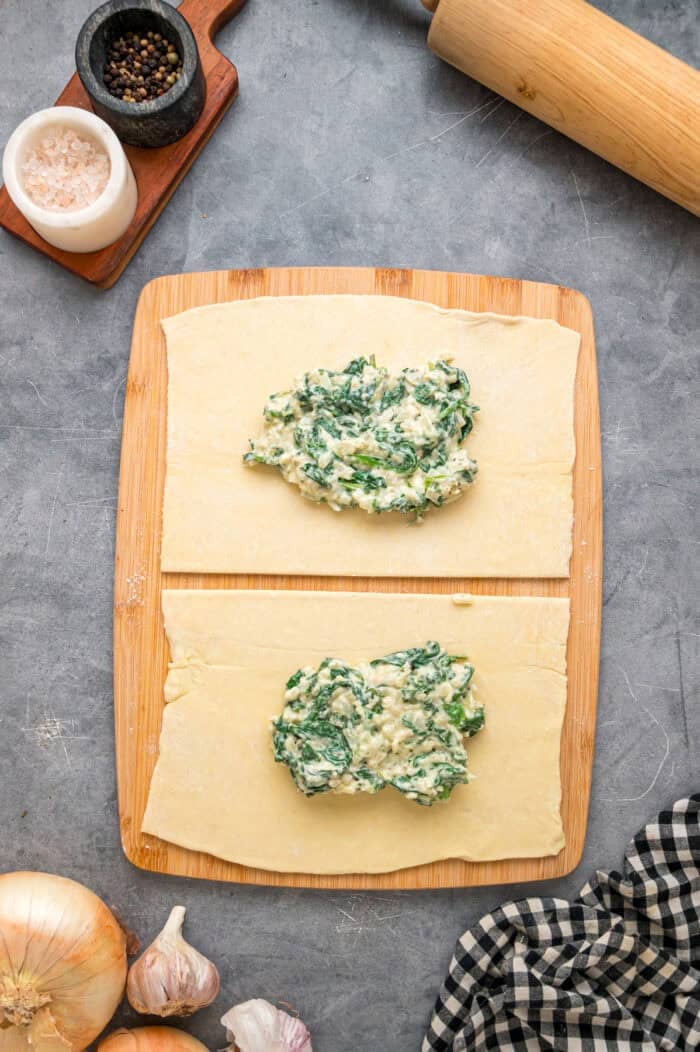 This Salmon Wellington recipe features tender salmon topped with a cream cheese spinach filling and wrapped in a flaky puff pastry. Spinach mixture on a puff pastry triangle.