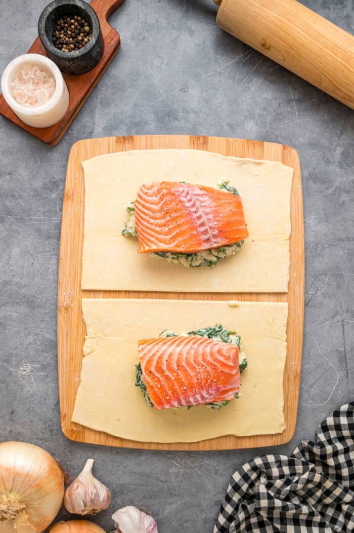 This Salmon Wellington recipe features tender salmon topped with a cream cheese spinach filling and wrapped in a flaky puff pastry. Salmon on top of the spinach mixture.