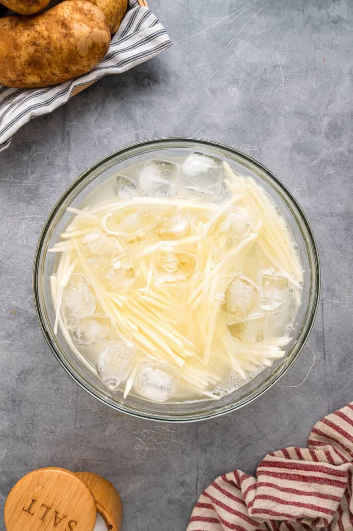 Made with just 3 ingredients, these Shoestring Fries are long, thin, and fry in just a few minutes. Serve with your favorite dipping sauces. Shoestring fries soaking in ice water
