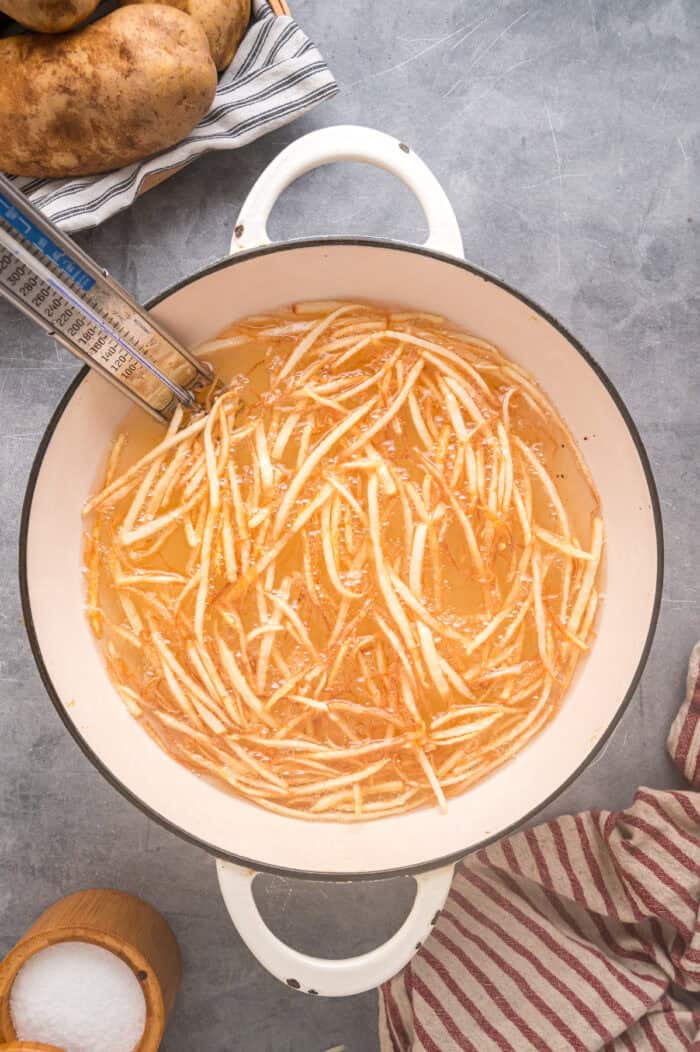 Made with just 3 ingredients, these Shoestring Fries are long, thin, and fry in just a few minutes. Serve with your favorite dipping sauces. Shoestring fries deep frying in oil
