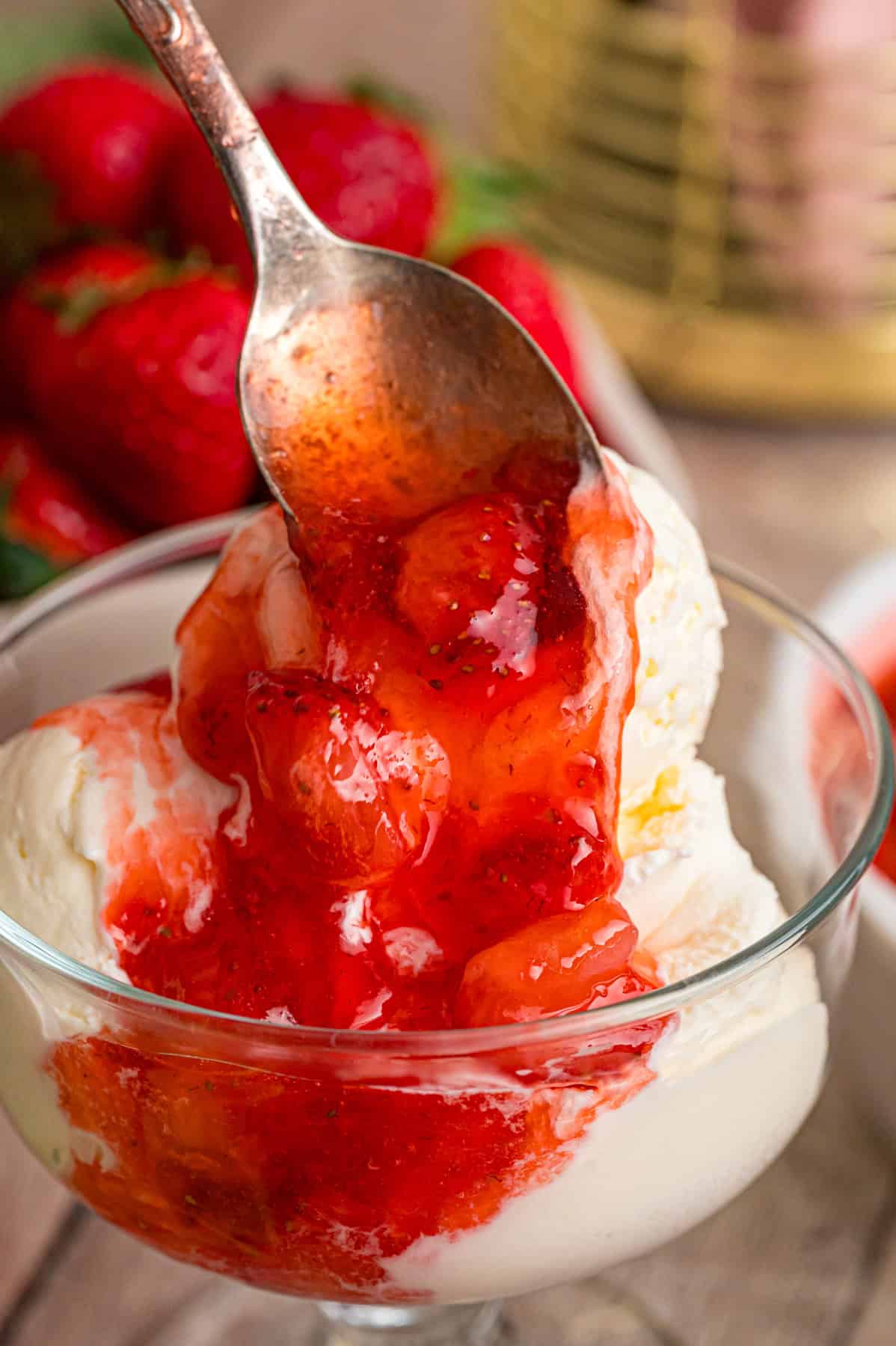 Drizzling strawberry sauce over vanilla ice cream