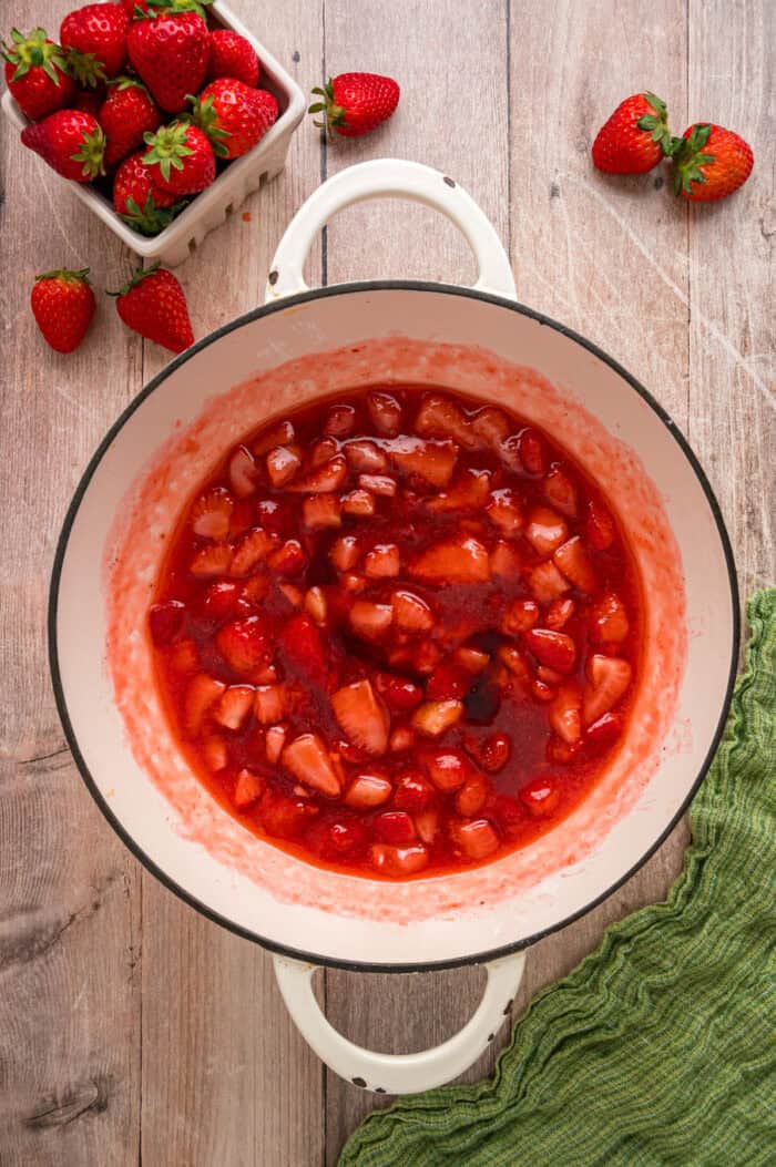 This easy Strawberry Sauce is made with just 6 ingredients in less than 20 minutes, with chunks of fresh strawberries in every bite. Vanilla added to strawberry sauce in a pan.