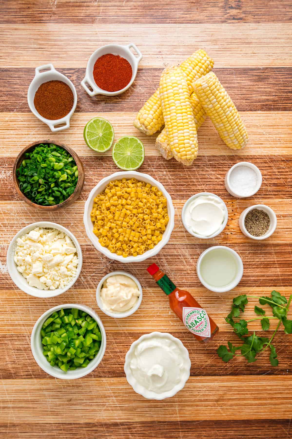 Charred corn kernels, cotija cheese, and pasta are tossed in a creamy dressing to make this Street Corn Pasta Salad. Overhead view of ingredients needed to make street corn pasta salad