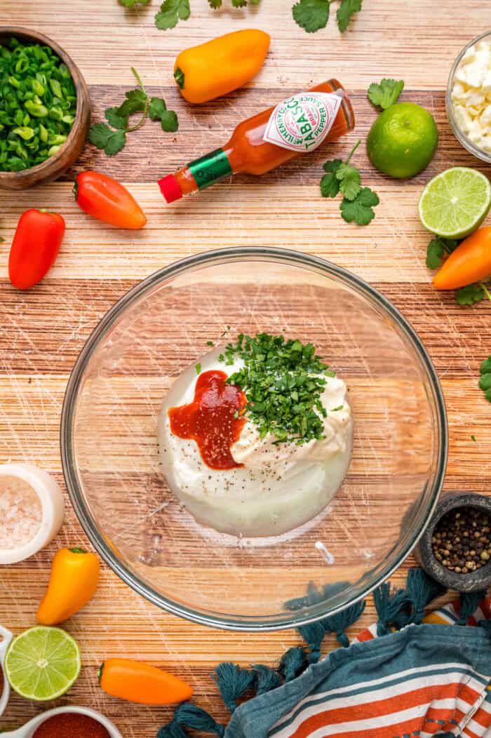 Charred corn kernels, feta cheese, and pasta are tossed in a creamy dressing to make this Street Corn Pasta Salad. Sour cream, Greek yogurt, mayo, cilantro, and spices in a bowl