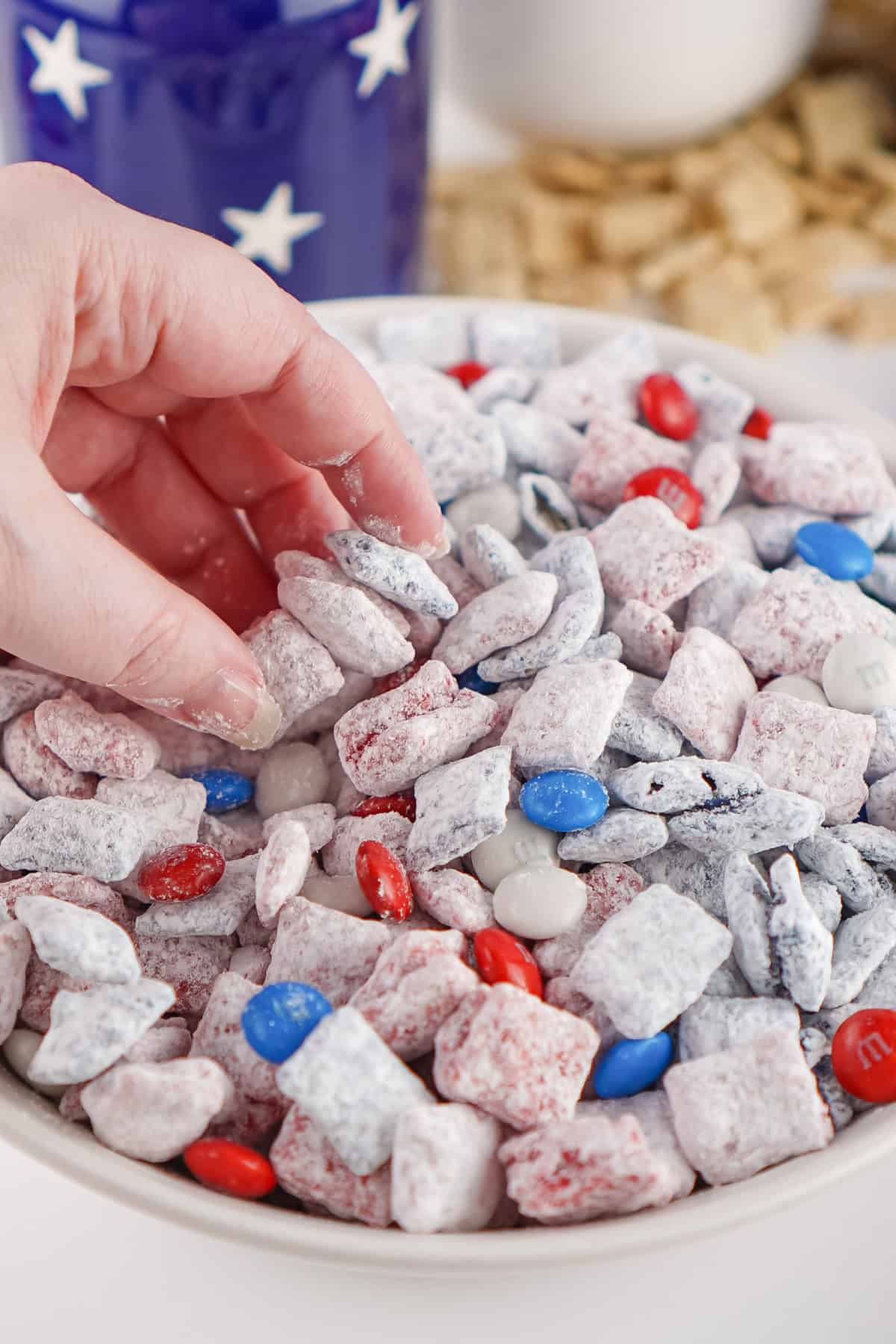 hand grabbing some 4th of July snack mix in a bowl