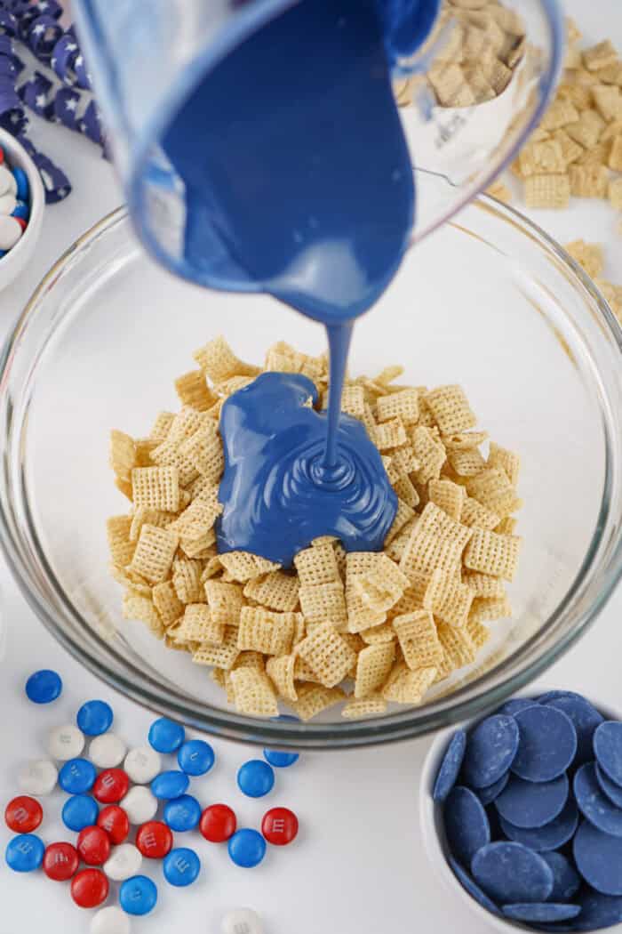 pouring the blue candy melts onto the Chex cereal.