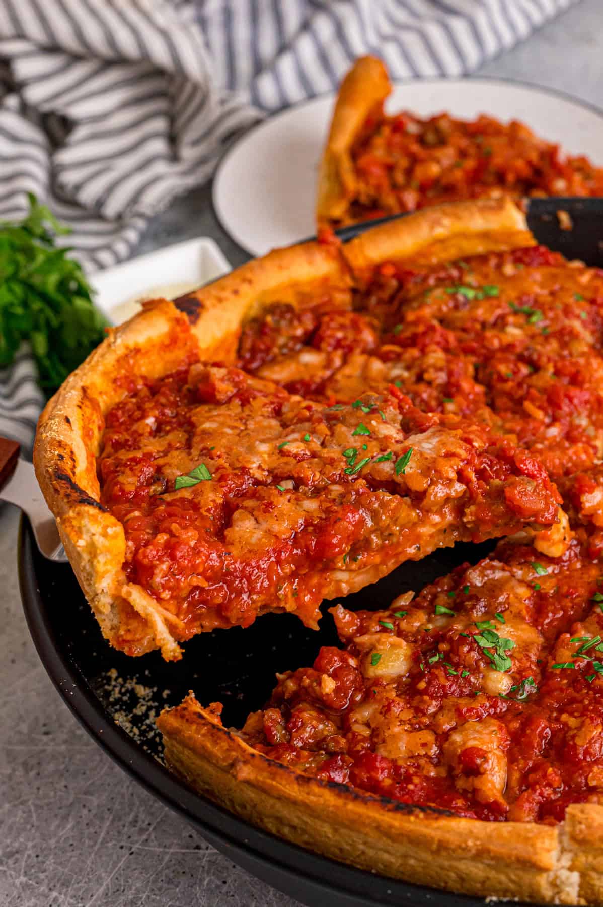 A slice of Chicago-style deep dish pizza being lifted out of the pan